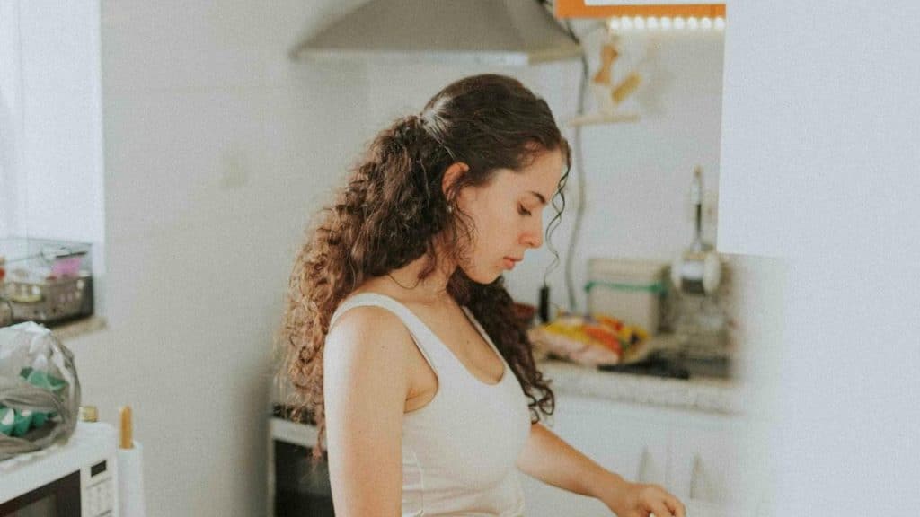 A woman standing in a kitchen, looking down while preparing something.