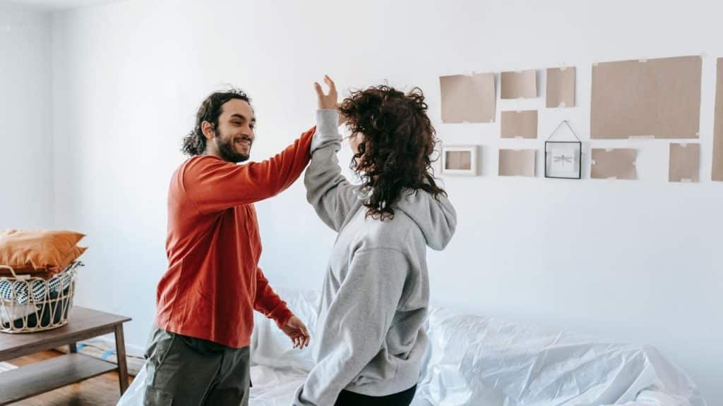 A man and woman high-fiving each other in a bright room.