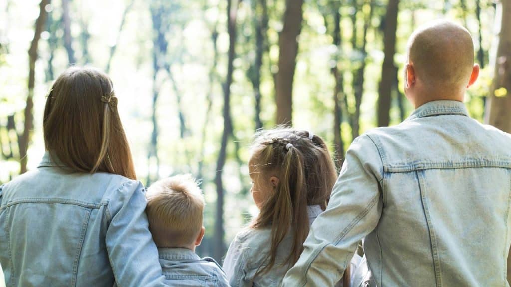 A picture of a family from behind outdoors.