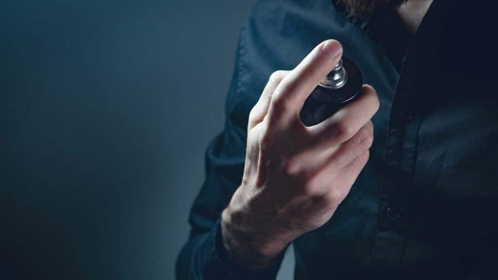 A man spraying perfume on his shirt.