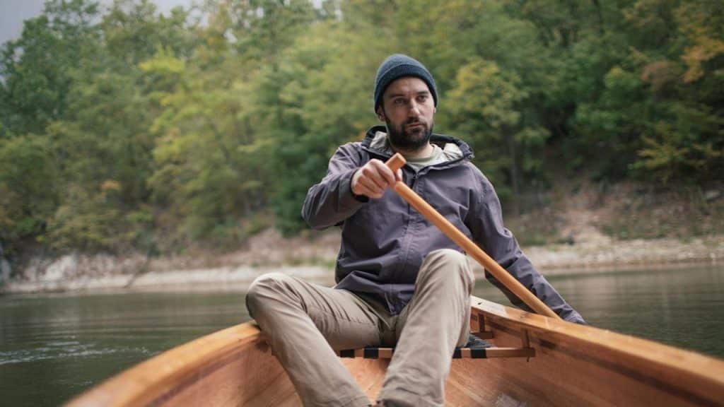 Man paddling canoe in the lake forest.