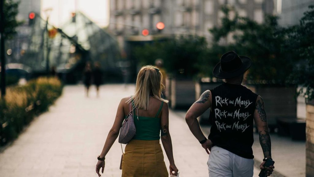 A man and a woman walking side by side on a city street at sunset.
