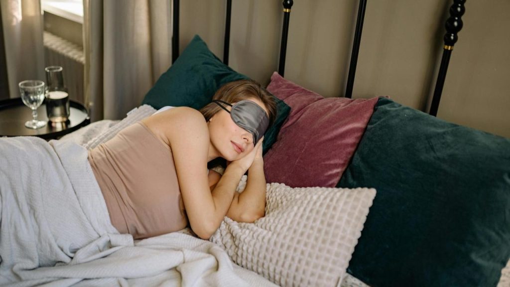 A woman sleeping on a bed wearing an eye mask.