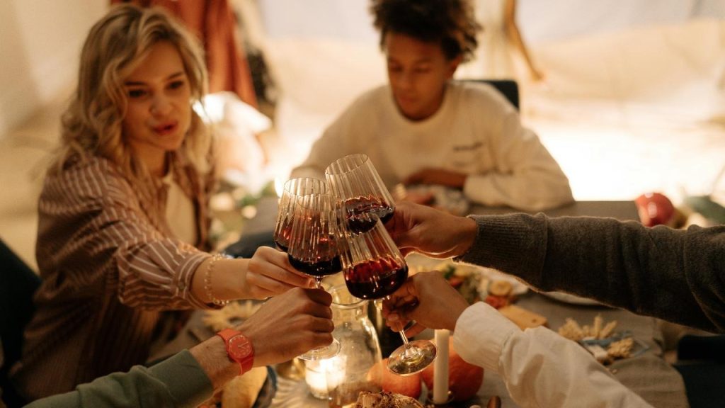 A group of people clinking glasses of red wine at a dinner table.