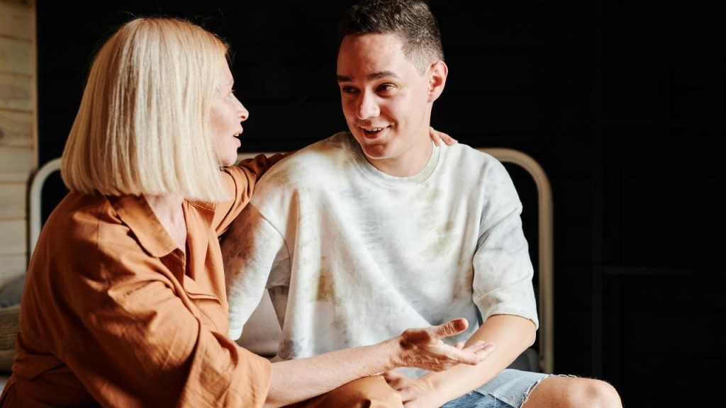 A woman and a young man smiling while talking together.
