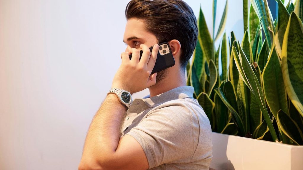 A man talking on a phone beside tall plants.