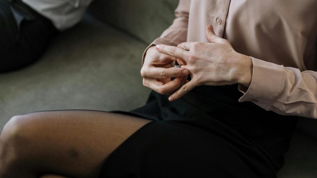 A person removing a ring while seated.