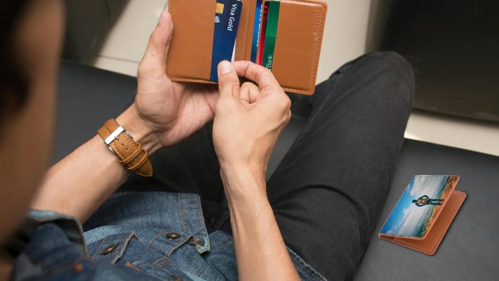 A person holding an open wallet with cards inside.