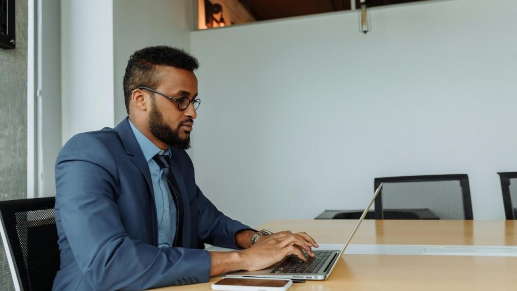 A man in a suit working on a laptop.