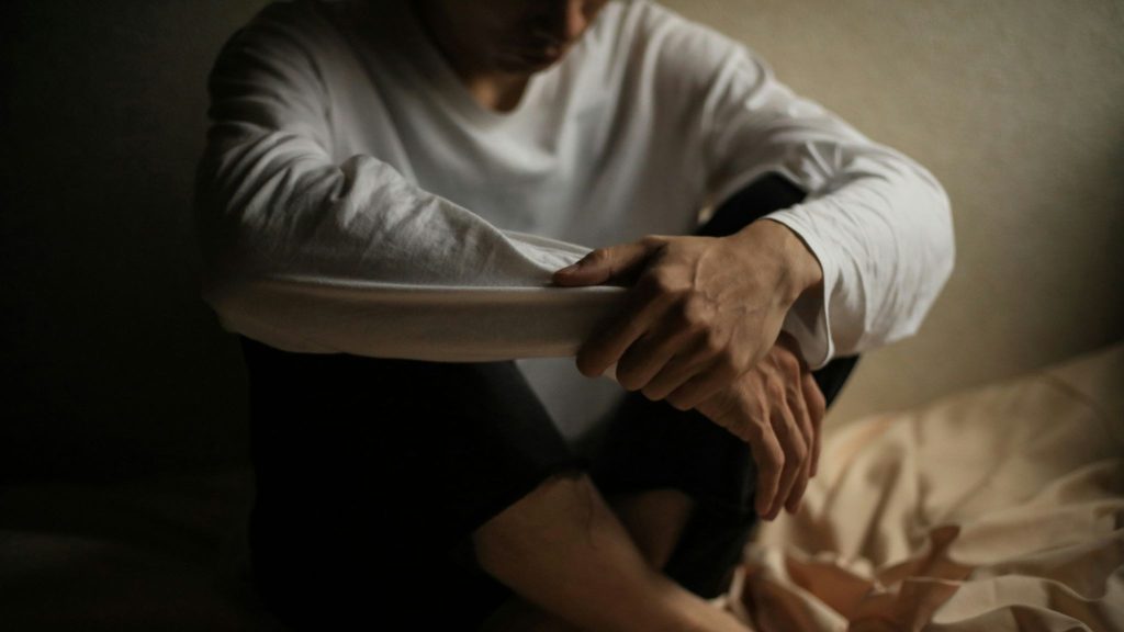 A man sitting at the bed alone