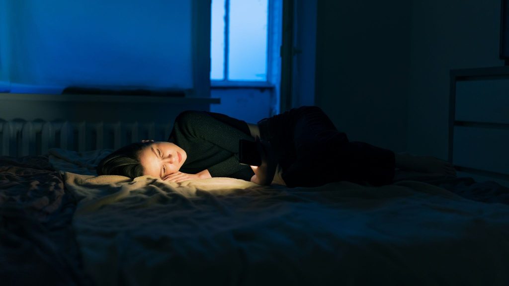 Woman using a phone while lying on the bed