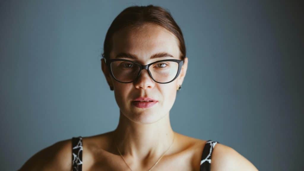 A close-up portrait of a woman with her hair pulled back wearing black cat-eye glasses.