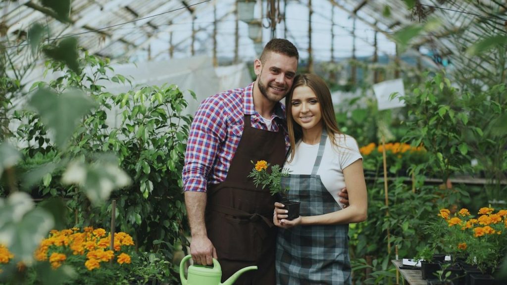 A couple tending plants in a greenhouse together.