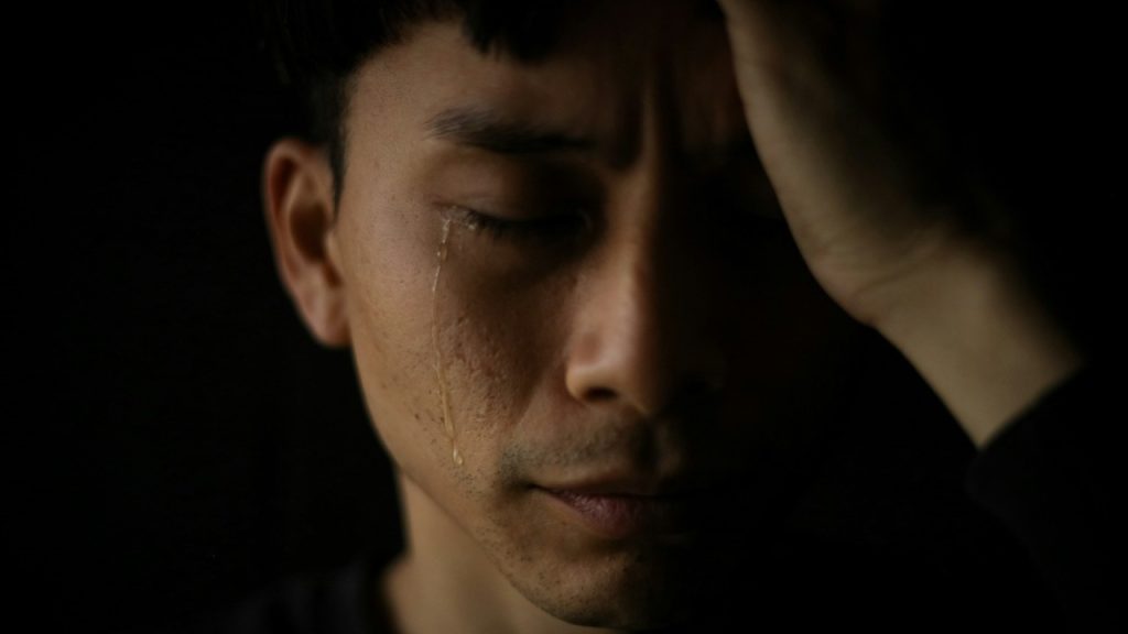 A close-up of a man crying with tears.