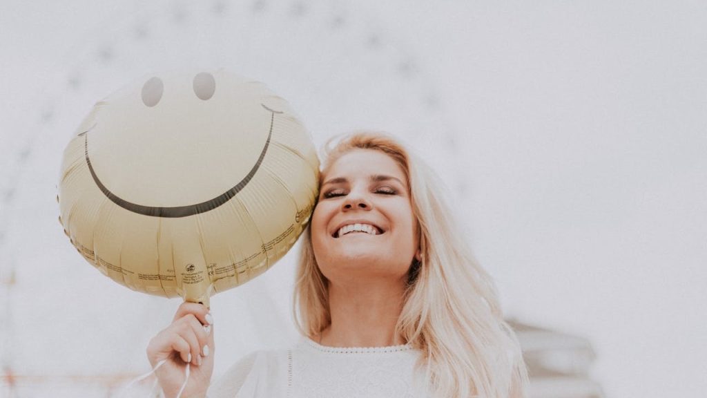 A contended woman holding a smiling balloon.