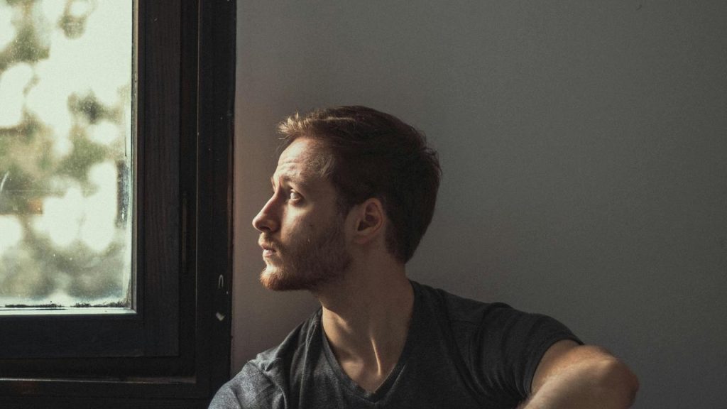 A man sitting by a window looking outside