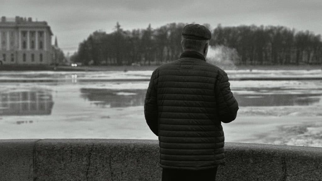 A man standing on a wall looking at a body of water.