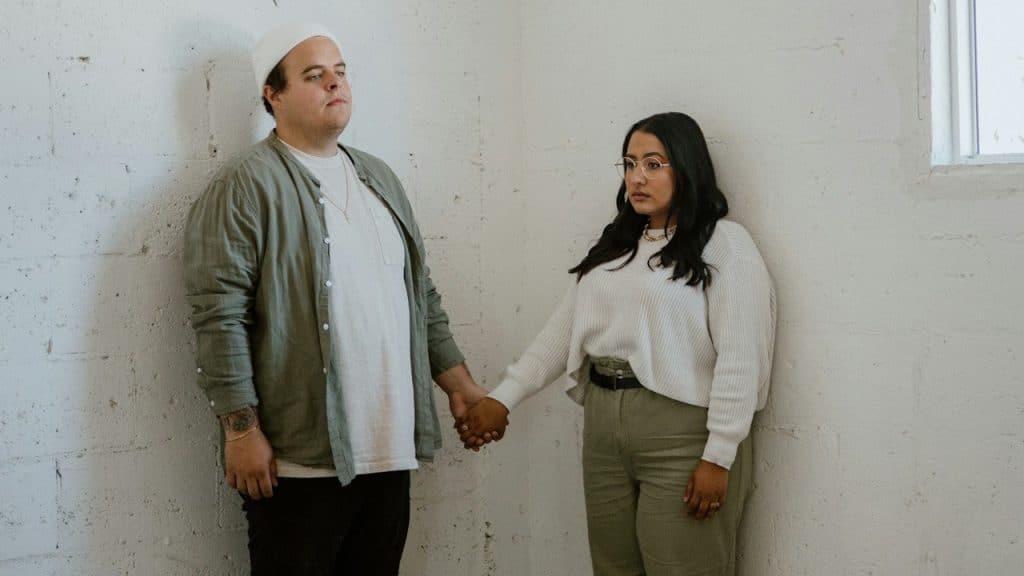 A man and a woman holding hands while standing in an empty room.