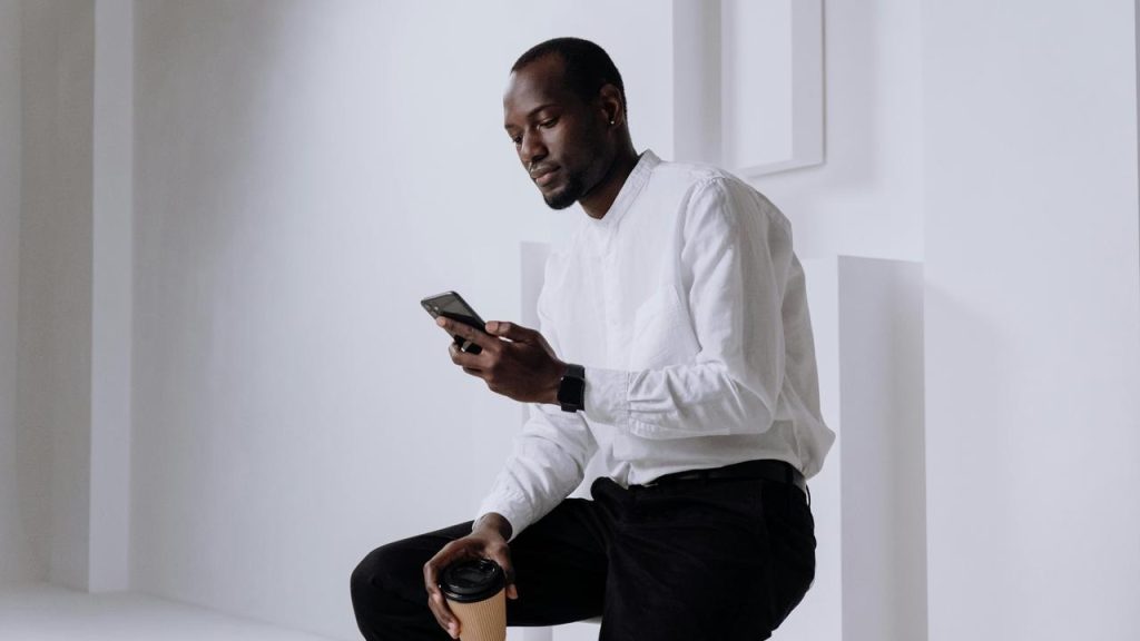 A man in a white shirt looking at his phone