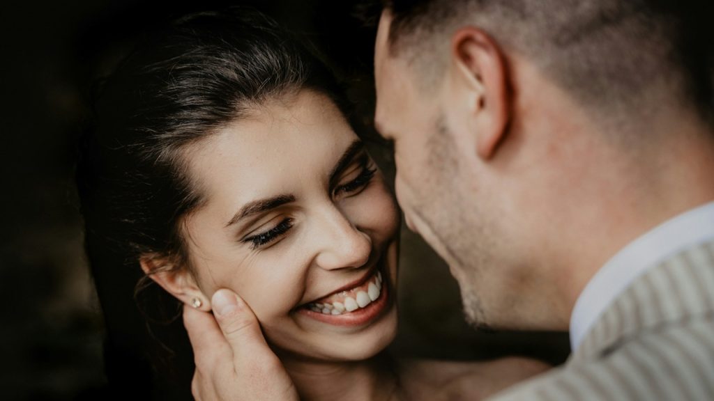 A man and woman smiling while standing close to each other.