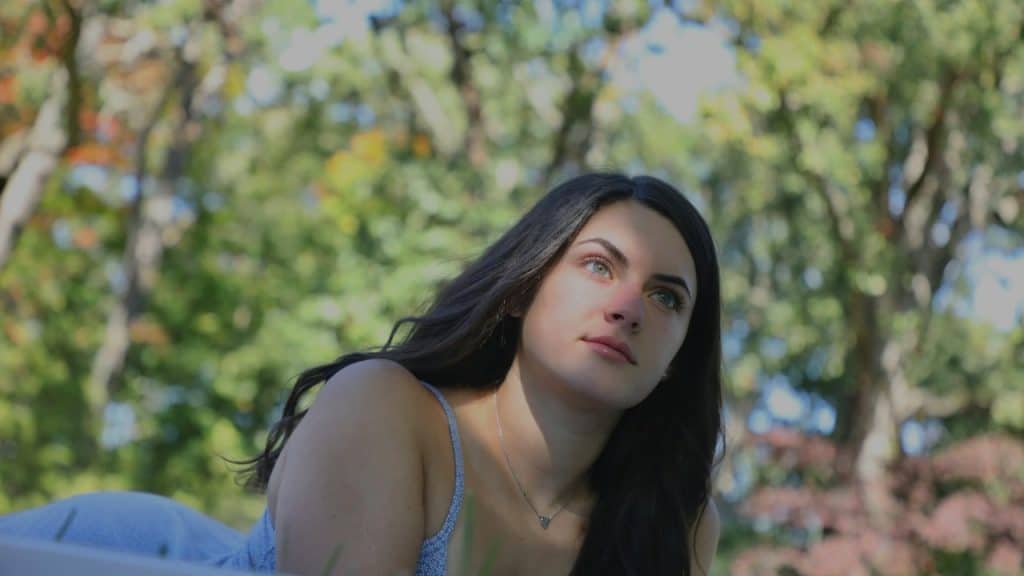 A woman looking lost in thought while sitting outside.
